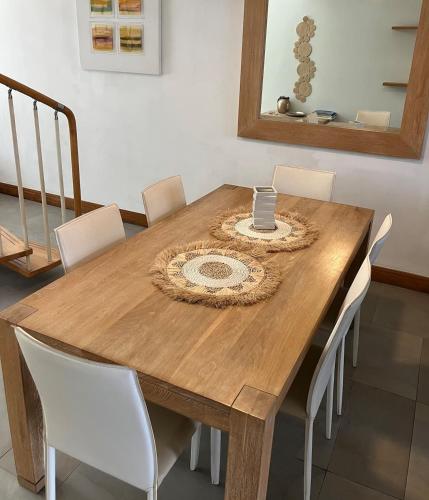 a wooden dining room table with white chairs around it at sea beach pool in Bain Boeuf