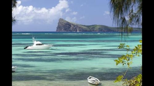 a white boat in the water with mountains in the background at sea beach pool in Bain Boeuf