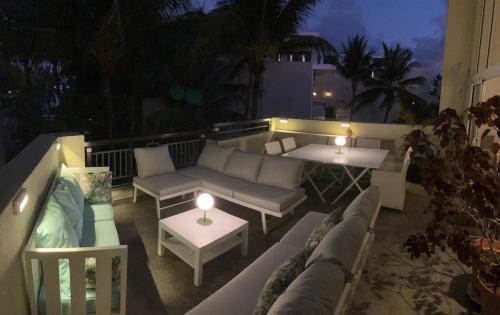 a patio with couches and tables on a balcony at night at sea beach pool in Bain Boeuf