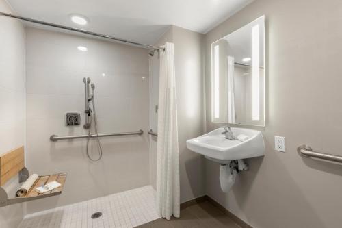 a white bathroom with a shower and a sink at Good Nite Inn Redwood City - San Francisco Airport in Redwood City