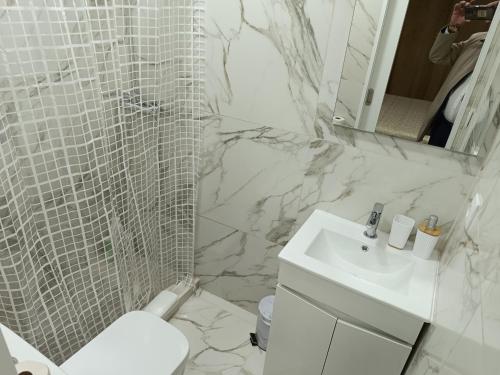 a white bathroom with a sink and a shower at Casa da Mina in Ponta Delgada
