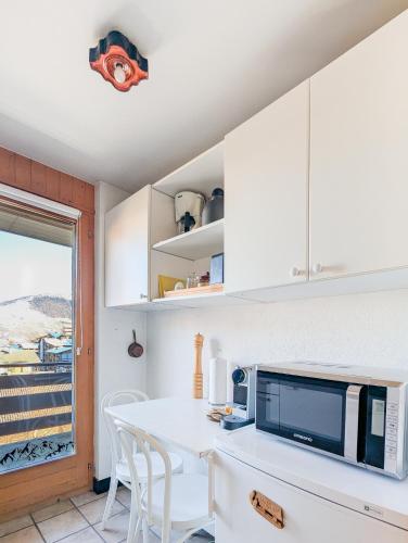 a kitchen with white cabinets and a table with chairs at Center of Nendaz ! Apartment 2 rooms with balcony in Nendaz
