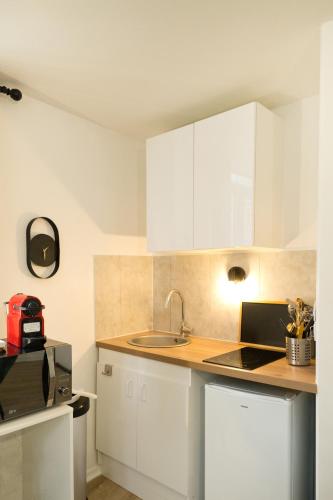 une cuisine avec des armoires blanches et un évier dans l'établissement Le Lounge - studio en Hypercentre, à Amiens