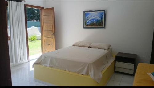 a bedroom with a bed with a picture on the wall at Suíte Santo in Santa Cruz Cabrália