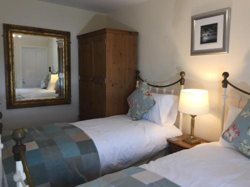 a bedroom with two beds and a mirror at Sea Breeze Cottage on the North Wales Coast in Penrhyn Bay