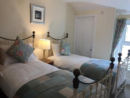 a bedroom with two beds and a lamp and a window at Sea Breeze Cottage on the North Wales Coast in Penrhyn Bay
