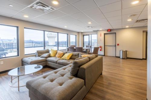 a living room with couches and a table and windows at Heart of Strip District - King Bd - Rooftop and Gym in Pittsburgh