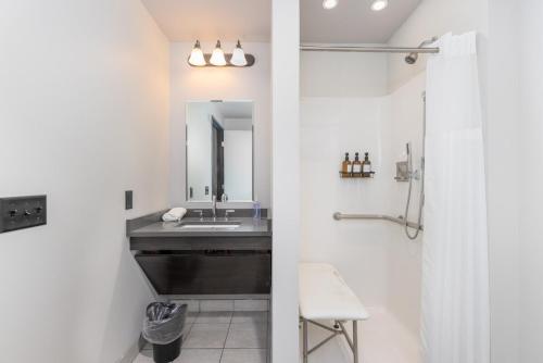 a bathroom with a sink and a mirror at Heart of Strip District - King Bd - Rooftop and Gym in Pittsburgh