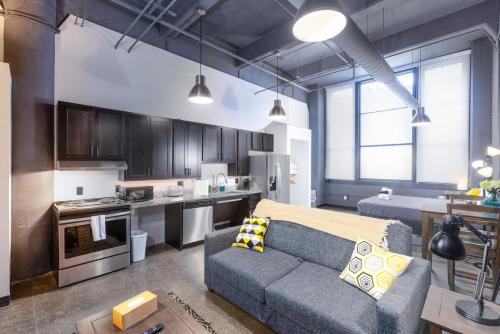 a living room with a couch and a kitchen at Heart of Strip District - King Bd - Rooftop and Gym in Pittsburgh