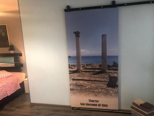 a wall with a poster of the ruins of a temple at B&B Filomena in Santa Giusta