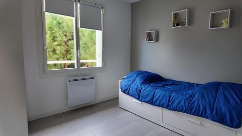 une chambre avec un lit avec une couverture bleue dans l'établissement Appartement cosy en bord de mer, aux Lecques