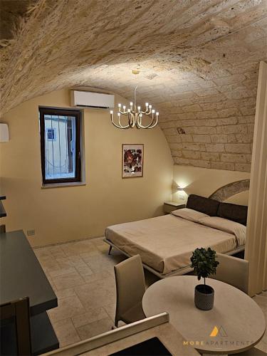 a bedroom with two beds and a table and a chandelier at More Apartments Blue Arch suite in Bari