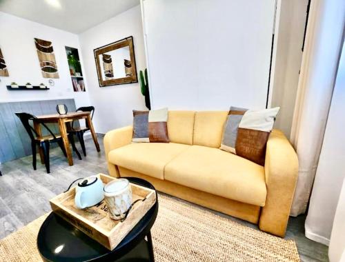 a living room with a yellow couch and a table at Le Refuge du Bord de Mer 2 pers- Studio avec parking à 500m de la mer in Houlgate