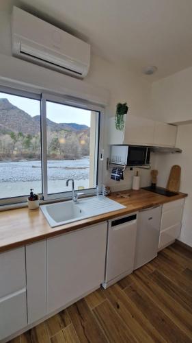 une cuisine avec un évier et une grande fenêtre dans l'établissement Au bord de la rivière, à Digne-Les-Bains