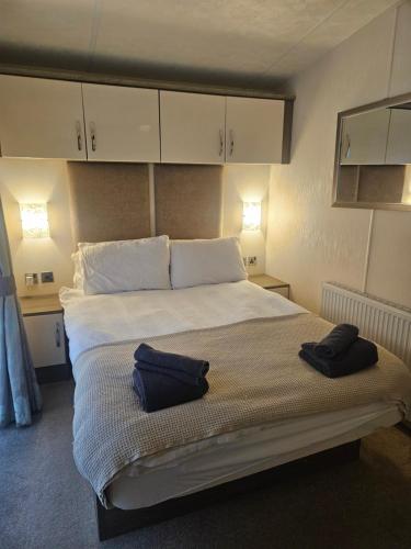 a bedroom with a large bed with two towels on it at Lakeside mini lodge in Saint Osyth