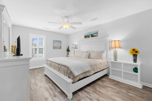 a white bedroom with a bed and a ceiling fan at NEW POOL & Spa Coming May 2025 - NEW HOT TUB Available now- Dog friendly 4BR private home 6Min Walk to Beach in Myrtle Beach
