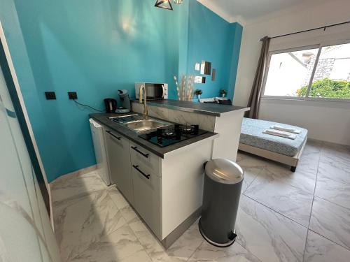 - une cuisine avec un évier et un mur bleu dans l'établissement La maison de Julia menton studio bleuté, à Menton