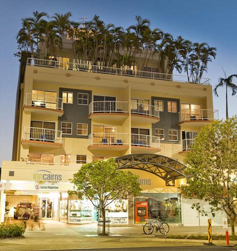 a tall building with palm trees in front of it at Inn Cairns in Cairns