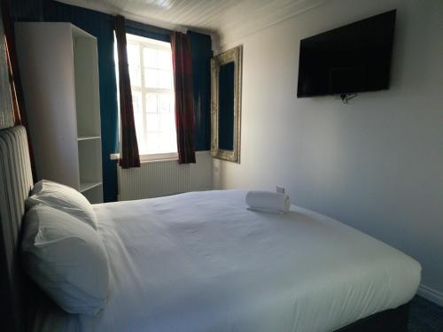 a bedroom with a white bed and a television at Ye Olde Hotel in Leuchars