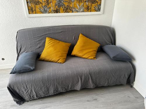 - un canapé gris avec 3 oreillers jaunes dans l'établissement T2 Familiaux - Confort & Plage à Pied, à Saint-Cyprien