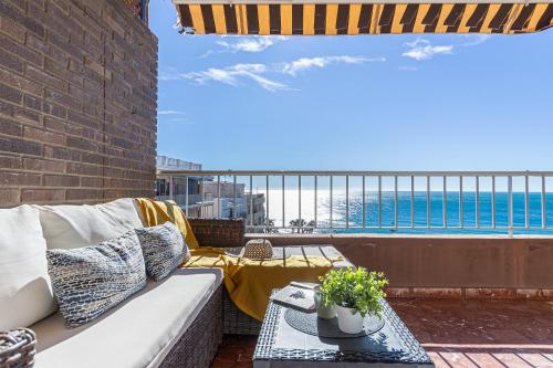 a couch on a balcony with a view of the ocean at Casa Mare Apartamento en primera línea de playa in Almuñécar