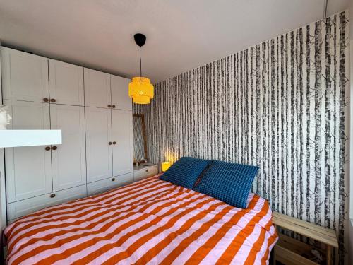 een slaapkamer met een bed met een gestreepte deken bij Bright & Cozy Central Studio in Reykjavík