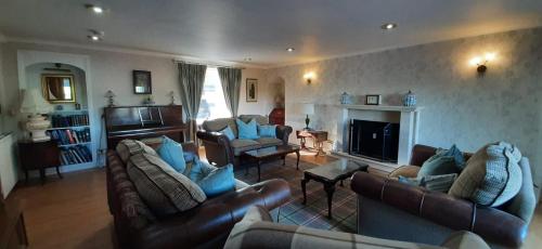 a living room with leather furniture and a fireplace at Marshill Farmhouse in Blackwood