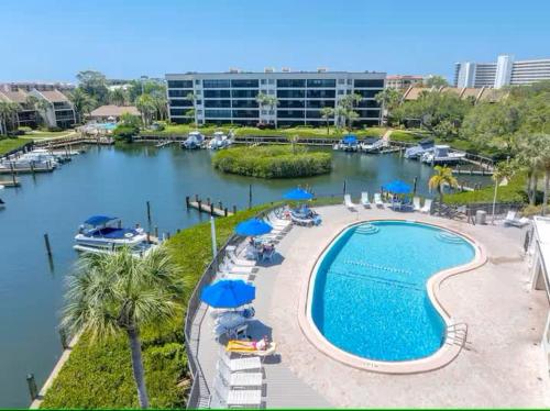 a swimming pool with umbrellas and a marina at Stunning 2BR Lagoon-View Steps To Siesta Key Beach in Sarasota