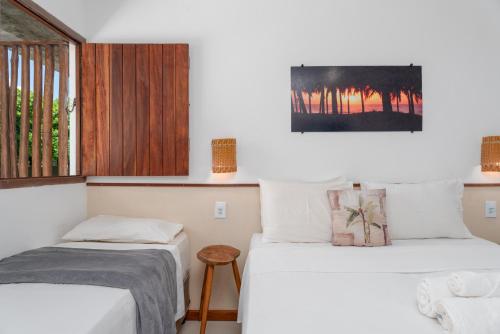 two beds in a room with a window at Pousada Trilha do Mar in Praia do Frances