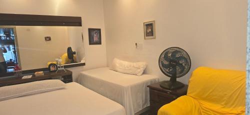 a room with two beds and a fan and a chair at Espaço TOP São Paulo - Brazil in Sao Paulo