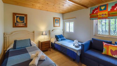 a bedroom with two beds and a couch at Cortijo el Alcornocal by Ruralidays in Villanueva de la Concepción
