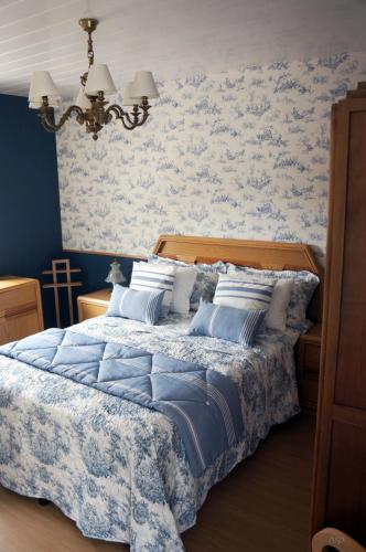 a bedroom with a blue and white bed with pillows at A pequena casa azul in Senhora das Febres