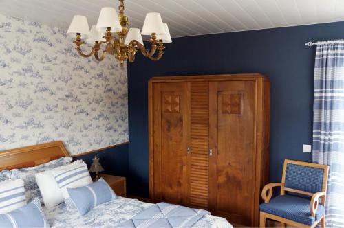 a bedroom with blue walls and a bed and a chandelier at A pequena casa azul in Febres