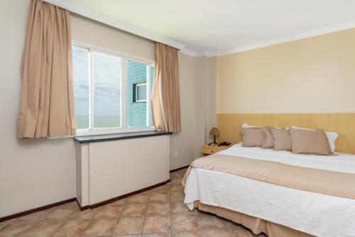 a bedroom with a large bed and a window at Hotel Atlantico Macaé By Inn House in Macaé