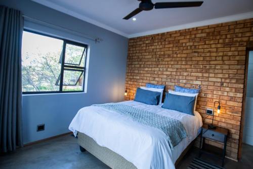 a bedroom with a brick wall and a bed with blue pillows at Sink Huis at Benlize in Pelindaba