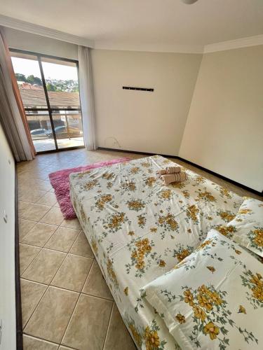a bedroom with a bed with a comforter on it at Casa Grande 3 quartos, perto parque Barigui in Curitiba