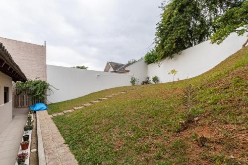 a grassy hill next to a white wall at Casa Grande 3 quartos, perto parque Barigui in Curitiba