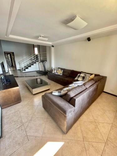 a living room with a leather couch and a table at Casa Grande 3 quartos, perto parque Barigui in Curitiba