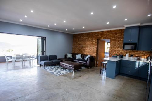 a living room with a couch and a table and a kitchen at Sink Huis at Benlize in Pelindaba