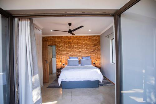 a bedroom with a bed and a brick wall at Sink Huis at Benlize in Pelindaba
