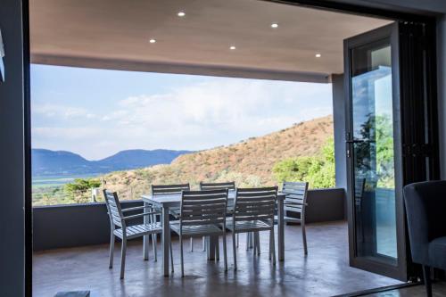 a dining room with a table and chairs and a large window at Sink Huis at Benlize in Pelindaba