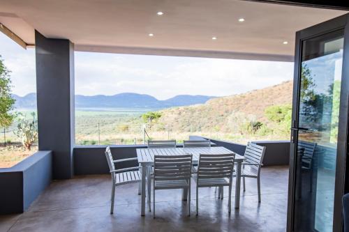 a dining room with a table and chairs and a large window at Sink Huis at Benlize in Pelindaba