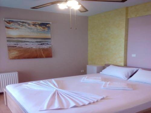 Un dormitorio con una cama blanca con un cuadro en la pared. en Apartment in Greece near the Sea with Garden, en Rafina