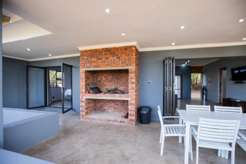 a living room with a fireplace and a table and chairs at Sink Huis at Benlize in Pelindaba