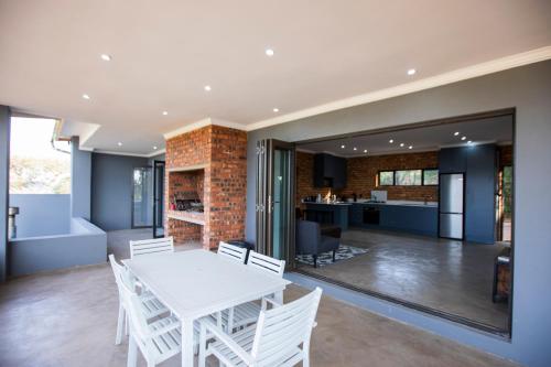 a dining room and kitchen with a white table and chairs at Sink Huis at Benlize in Pelindaba