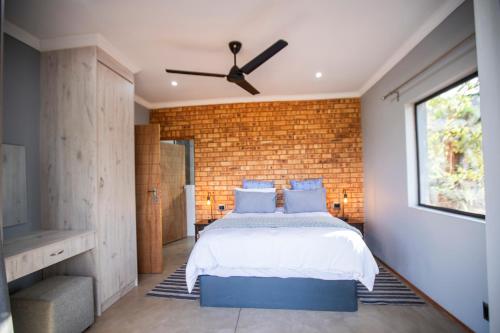 a bedroom with a bed and a brick wall at Sink Huis at Benlize in Pelindaba