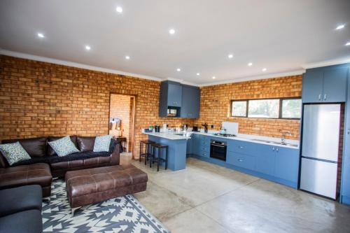 a living room with a couch and a kitchen at Sink Huis at Benlize in Pelindaba