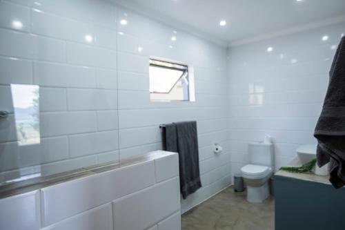a white bathroom with a tub and a toilet at Sink Huis at Benlize in Pelindaba