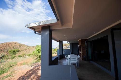 a balcony with white chairs and a view of the mountains at Sink Huis at Benlize in Pelindaba