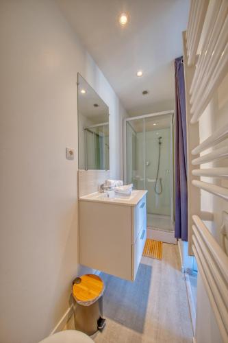 une salle de bain blanche avec un lavabo et un miroir dans l'établissement Horizon Houzeau, à Reims